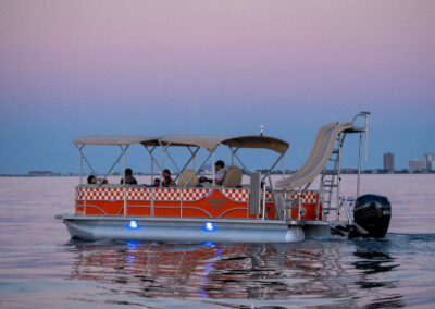 Family enjoying charter pontoon boat with slide and captain.