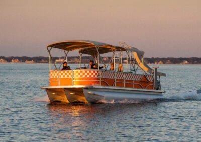 Family enjoying charter pontoon boat with slide and captain.