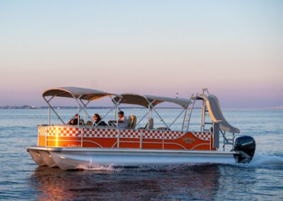 Family enjoying charter pontoon boat with slide and captain.