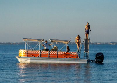 Family enjoying charter pontoon boat with slide and captain.